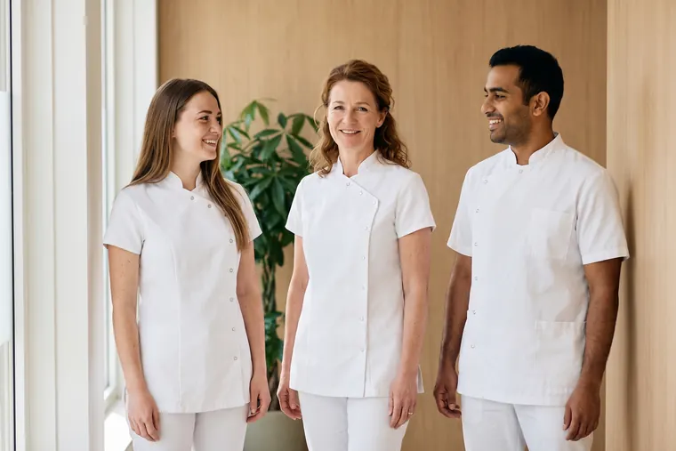 Three colleagues of the practice stand together in the treatment room, smiling